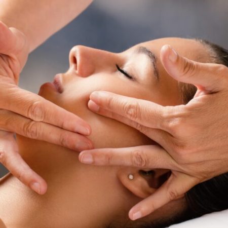 Close up portrait of woman having facial cosmetic therapy. Therapist applying cream on female cheek.